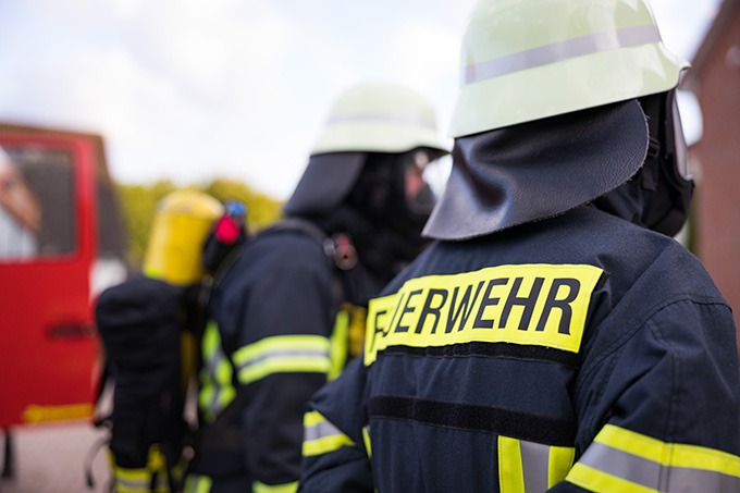 Symbolbild Feuerwehr mit Feuerwehrmann vor einem Feuerwehrauto